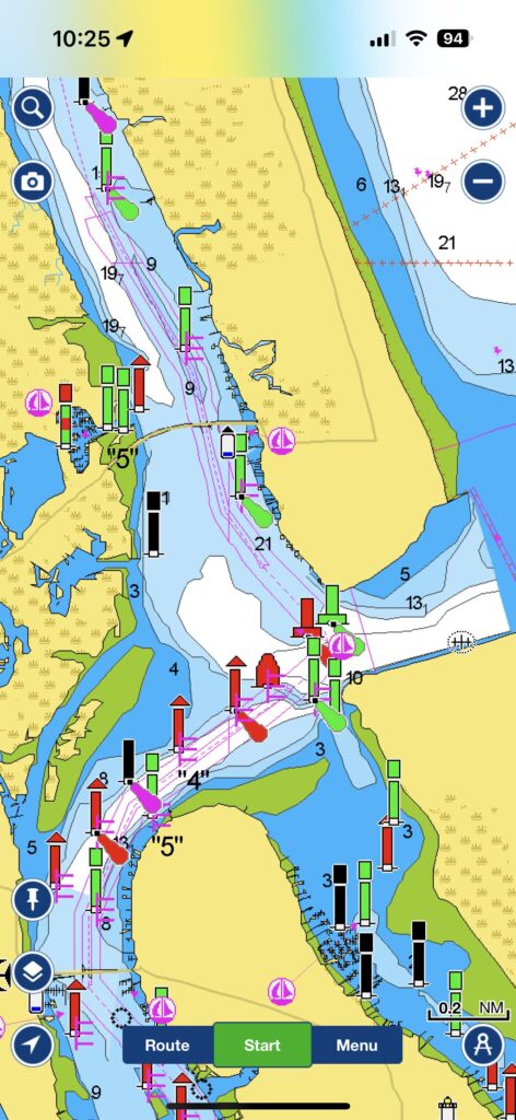 Screenshot of a nautical chart showing a waterway with marked channels, buoys, and navigational aids. The chart highlights water depths, indicated by color gradations, with green, red, and black markers showing navigational routes. The map also features route and start options at the bottom, suggesting the use of a navigation app for boating. Various symbols indicate marinas, hazards, and other key points of interest along the route.